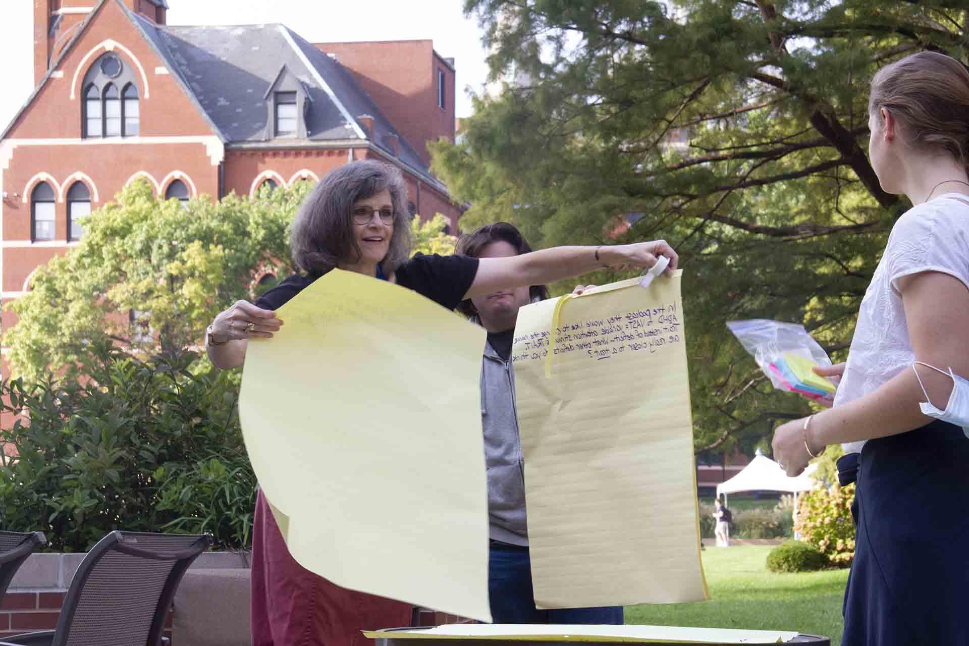 Students hold up a display during an outdoor class discussion.