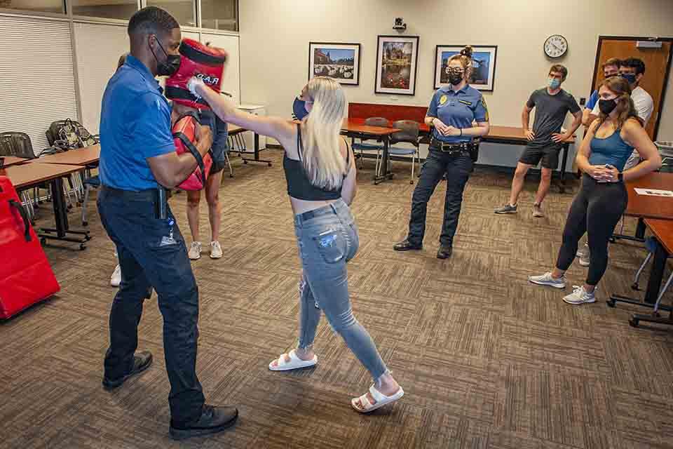 Participants stand around while one group member practices hitting a foam target.